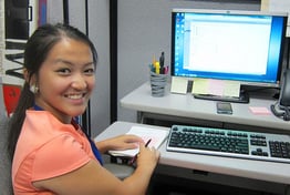 A student sitting at a desk with a computer keyboard and monitor.